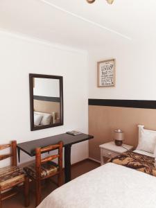 a bedroom with a bed and a desk with a mirror at Sunflower Self-Catering in Walvis Bay