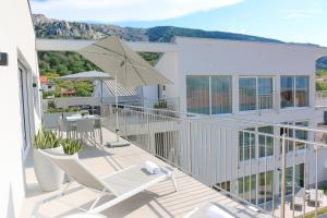 a balcony of a house with chairs and an umbrella at Apartment Baska, exklusive Apartments mit Poolarea in Baska, Krk - Kroatien in Baška +206 photos