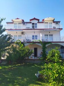 a large white building with a balcony on top of a yard at Apartmant Sučić in Kaštela