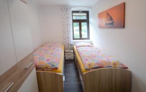 2 Betten in einem kleinen Zimmer mit Fenster in der Unterkunft Ferienwohnung Villa AusZeit in Königstein an der Elbe