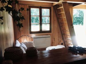 een kamer met een tafel, 2 stoelen en ramen bij La cabane du pêcheur in Montcuq