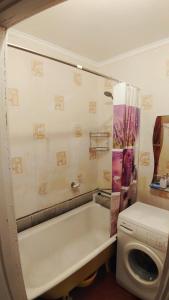 een badkamer met een bad en een wasmachine bij квартира на вулиці Лесі Українки in Uzyn