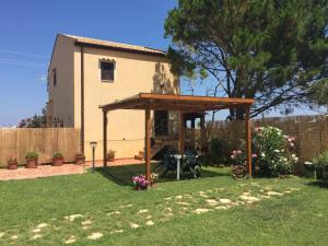 a backyard with a house and a wooden pergola at Casa del Sale, a 50 m dalla spiaggia in Lascari