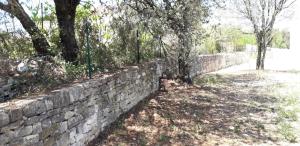 a brick retaining wall with trees and a sidewalk at Au Clos des Faysses in Orgnac-lʼAven
