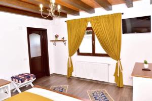 a bedroom with a window with yellow curtains at Căsuța de Poveste in Târgu Neamț