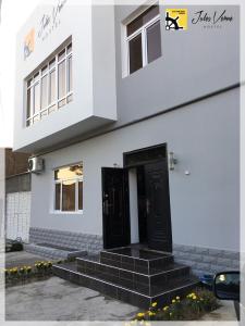 a black door on a white building with stairs at Jules Verne Hostel in Tashkent