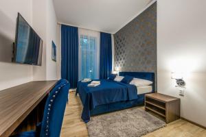 Habitación de hotel con cama azul y TV en Hotel Black Horse, en Prešov