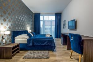a blue bedroom with a blue bed and a desk at Hotel Black Horse in Prešov