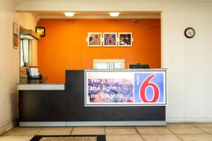 a reception desk with an orange wall and a sign at Motel 6-Brinkley, AR in Brinkley