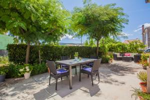 a table and chairs in a yard with trees at Apartman Madlen in Cres