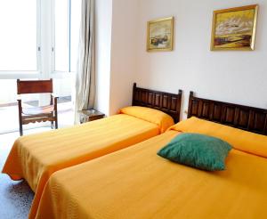 two beds in a hotel room with yellow sheets at Hostal Can Marinés in Sant Carles de la Ràpita