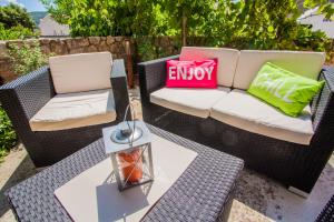 two wicker chairs and a table on a patio at Apartman Madlen in Cres