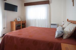 ein Schlafzimmer mit einem Bett mit einer orangefarbenen Decke und einem Fenster in der Unterkunft Apartamentos Turisticos Ceu Azul in Arcozelo