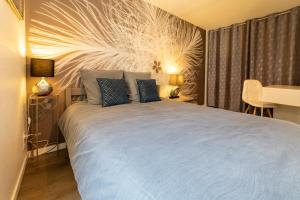 a bedroom with a bed with blue sheets and a table at Le Félix Grat - LAVALOC in Laval