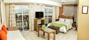 a bedroom with a bed and a tv and a couch at La Rozada Suites in Corrientes