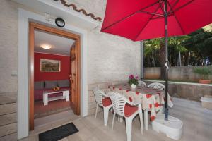 Mihaela Apartments في بوريتش: طاولة وكراسي مع مظلة حمراء على الفناء