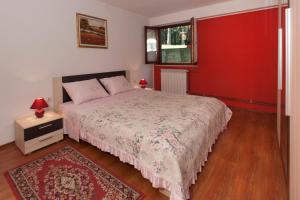 Mihaela Apartments في بوريتش: غرفة نوم بسرير وجدار احمر