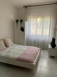 a white bedroom with a bed and a window at Casa Ohana in Serramanna