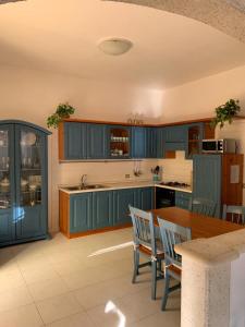eine Küche mit blauen Schränken sowie einem Tisch und Stühlen in der Unterkunft Casa Ohana in Serramanna