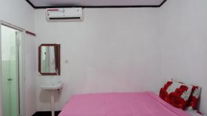 龙目岛库塔Perwita Homestay的卧室配有粉红色的床和水槽