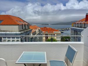 stół i krzesło na balkonie z budynkami w obiekcie Portosín -Suites w mieście Portosin