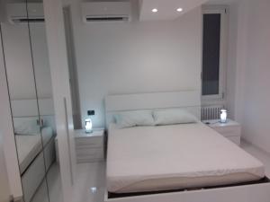 Habitación blanca con cama y espejo en imperatrice, en San Remo