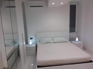 a white bedroom with a bed and a mirror at imperatrice in Sanremo