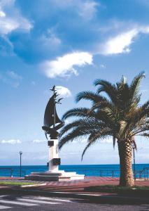 a statue next to a palm tree and the ocean at Zefiro Residence in Siderno Marina