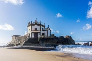 a church on the beach next to the ocean at Apartamentos Turisticos Ceu Azul in Arcozelo