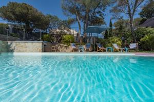 una piscina con sillas y sombrillas en Villa Perle De La Mer, en Saint-Aygulf