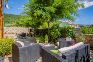 eine Terrasse mit Korbstühlen und einem Baum in der Unterkunft Apartman Madlen in Cres