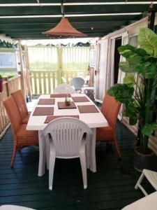 a white table and chairs on a deck with a table and chairs at Mobil-home 6 personnes in Mimizan
