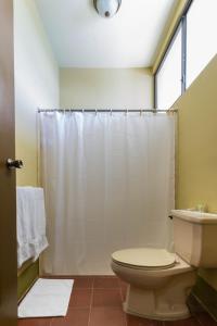 y baño con cortina de ducha blanca y aseo. en Hotel Frontera, en Ocotal