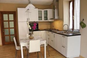 a kitchen with white cabinets and a table with flowers on it at La Piccola Oasi Toscana in Bagni di Lucca