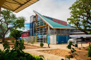 a large glass building with a blue roof at Dunia Hôtel Ouagadougou Loumbila in Loumbila