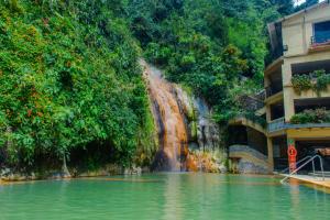 a waterfall next to a building next to a body of water at Termales Santa Rosa De Cabal in Santa Rosa de Cabal