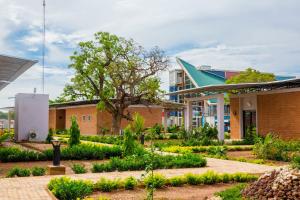 a garden in front of a building with a tree at Dunia Hôtel Ouagadougou Loumbila in Loumbila