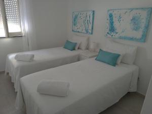 2 Betten in einem weißen Zimmer mit blauen Akzenten in der Unterkunft Casa da avó Lu in Olhão