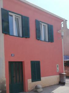 a red building with green shutters on it at Novalja centar in Novalja +12 photos