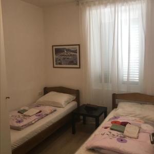two beds in a small room with a window at Novalja centar in Novalja
