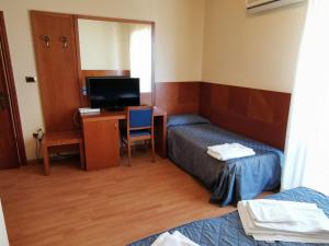 a room with two beds and a desk with a television at Hotel Calgary in Casalbordino