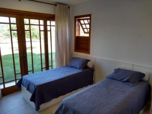 two beds in a room with a window at PRAIA DO FORTE - CONDOMINIO VILLAGE DAS ACACIAS - PISCINAS NATURAIS in Praia do Forte +39 photos