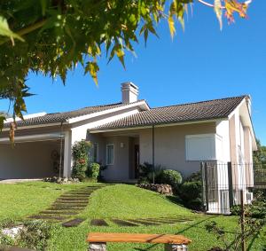 una casa blanca con césped delante en Casa Colina do Sol, en Nova Petrópolis