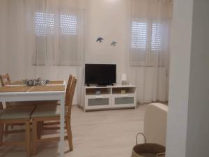 ein Wohnzimmer mit einem TV und einem Tisch mit Stühlen in der Unterkunft Casa da avó Lu in Olhão