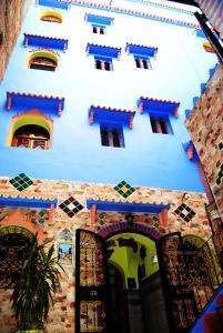 
a building that has a clock on the side of it at Hotel Casa Khaldi in Chefchaouen
