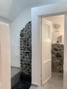 una puerta que conduce a una habitación con una pared de piedra en Timedrops Santorini Villas, en Emporio