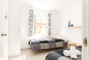 マラガにあるSuite Homes La Victoriaのベッドルーム1室(ベッド2台、鏡付)