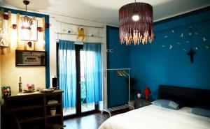 sypialnia z niebieskimi ścianami, łóżkiem i żyrandolem w obiekcie Fabio Room Cercola w mieście Cercola