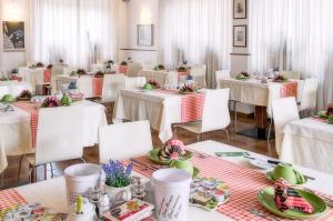 a dining room with white tables and white chairs at Hotel Erika in Malcesine