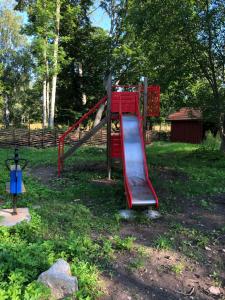 plac zabaw z czerwoną zjeżdżalnią w parku w obiekcie Nedanby | Cottage | Idyllic location | Porch | Grill w mieście Edsbro